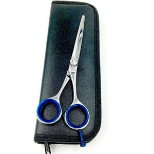 Stainless steel beard and mustache scissors with blue finger inserts resting on black zippered carrying case – The Simple Man grooming tools.