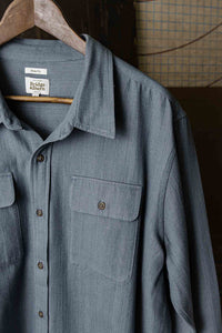 Close-up of denim herringbone Bedford Shirt collar and chest pockets on hanger.