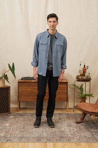 Man wearing denim herringbone Bedford Shirt from The Simple Man, layered with dark jeans.