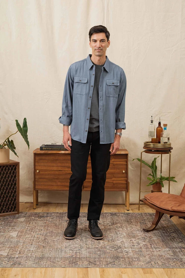 Man wearing denim herringbone Bedford Shirt from The Simple Man, layered with dark jeans.