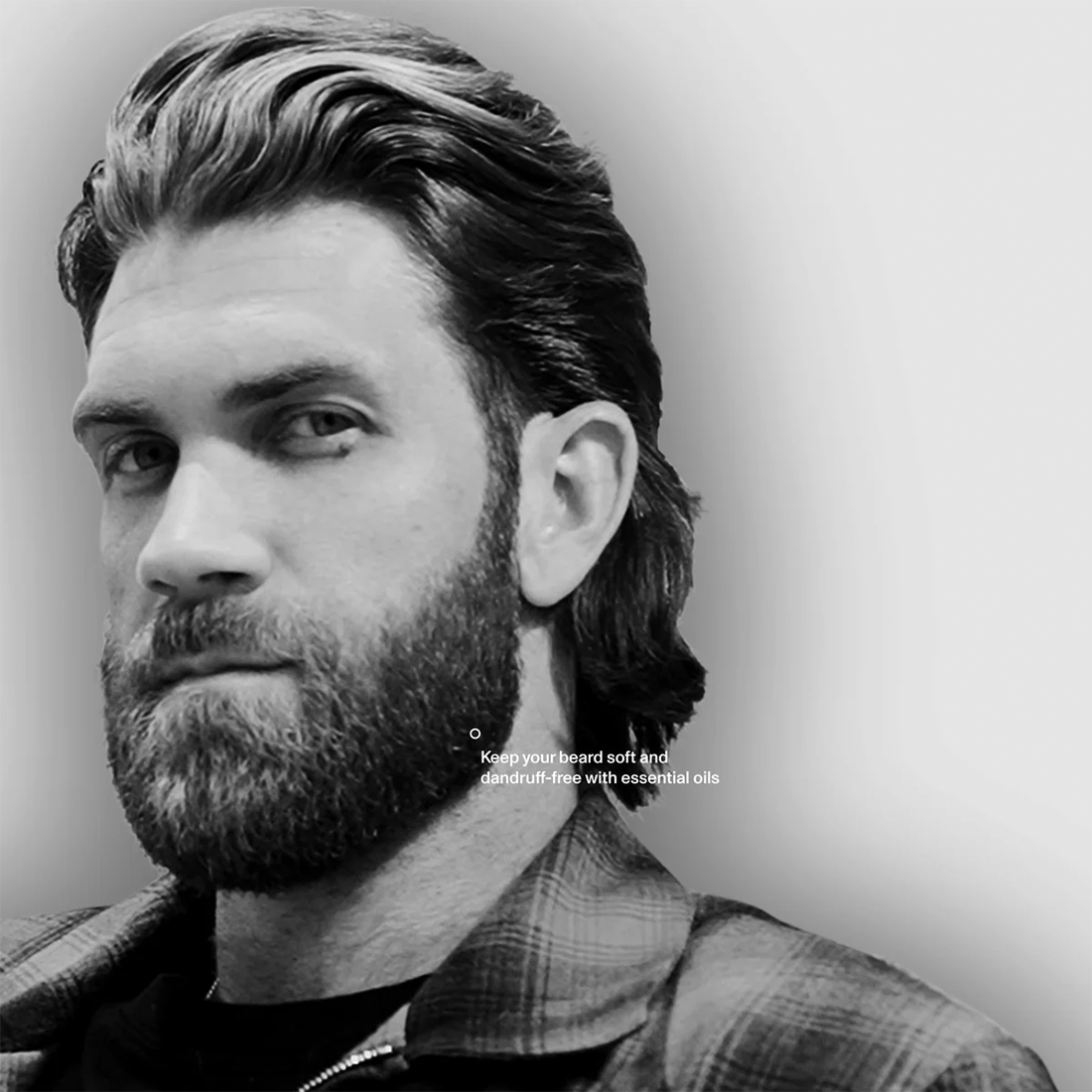 Black and white portrait of a man with a full beard and swept-back hair, captioned about soft, dandruff-free beards