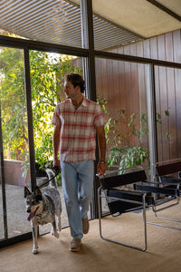 Men's coral multi cotton linen plaid shirt – lifestyle shot on model walking with dog in mid-century modern home interior