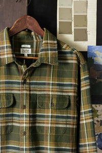 The Cole Slim Shirt by Bridge & Burn in Mountain Green plaid shown on wooden hanger, highlighting slim fit and double chest pocket construction