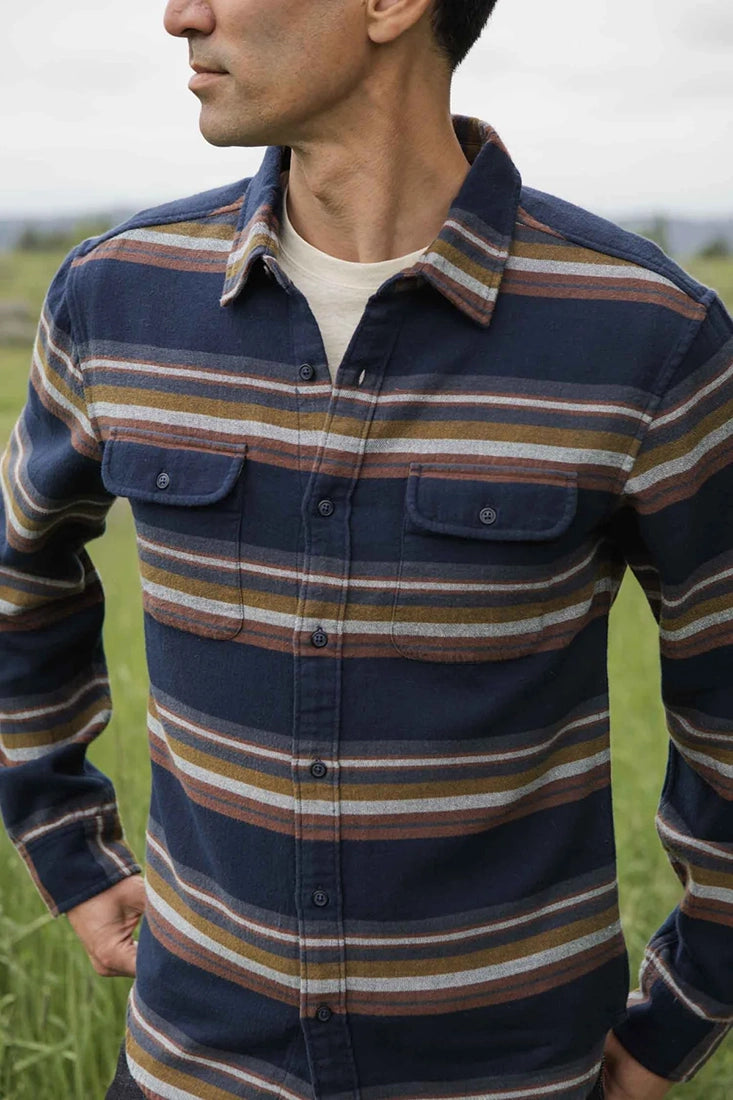 Bridge & Burn Coastline Stripe Shirt – Navy flannel shirt with brown, gold, and gray stripes worn open field – The Simple Man