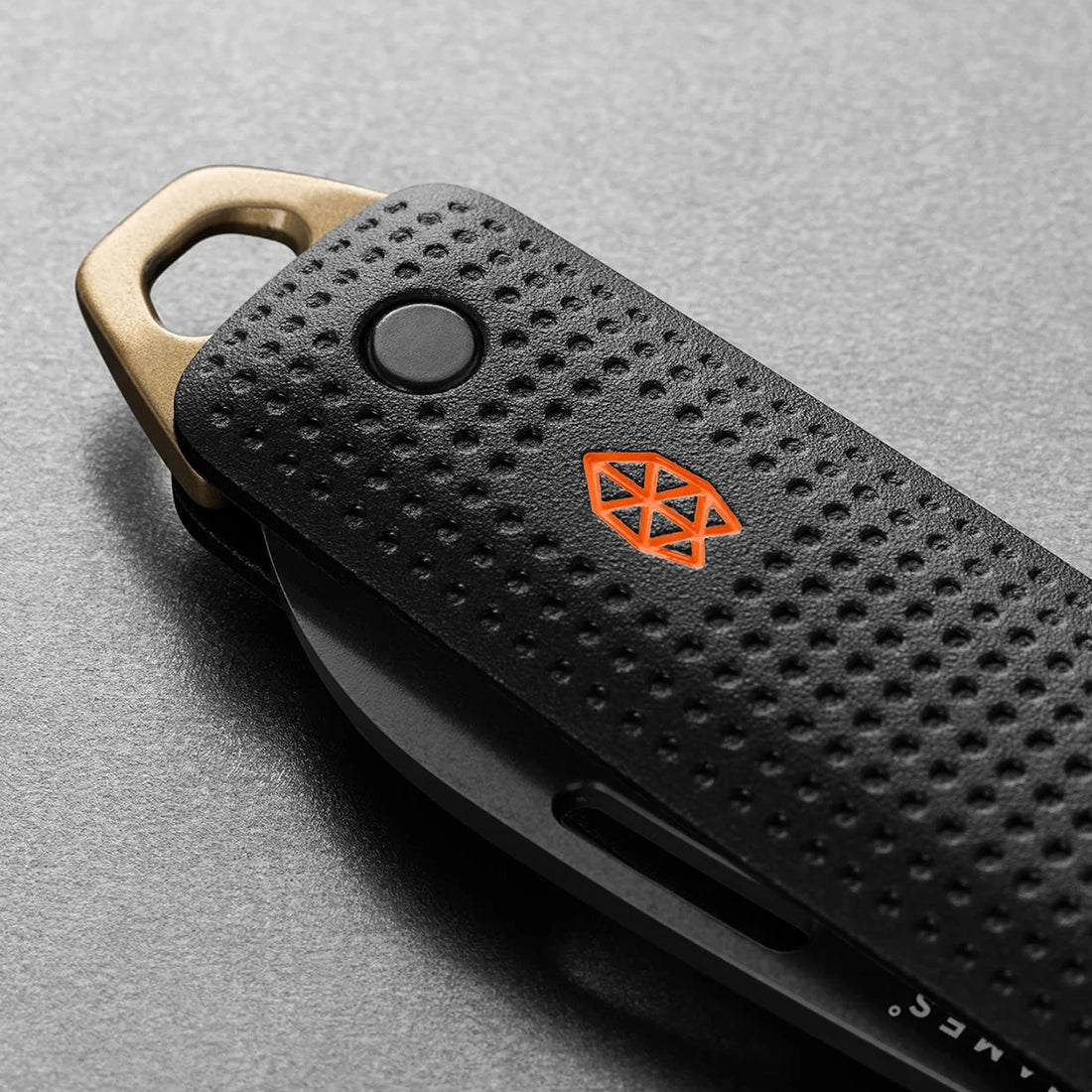 The James Brand Elko Black and Fire close-up — black machined aluminum handle orange logo bronze key ring detail