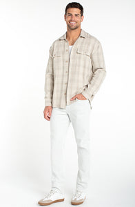Full body view of men wearing oatmeal plaid overshirt with light pants and sneakers