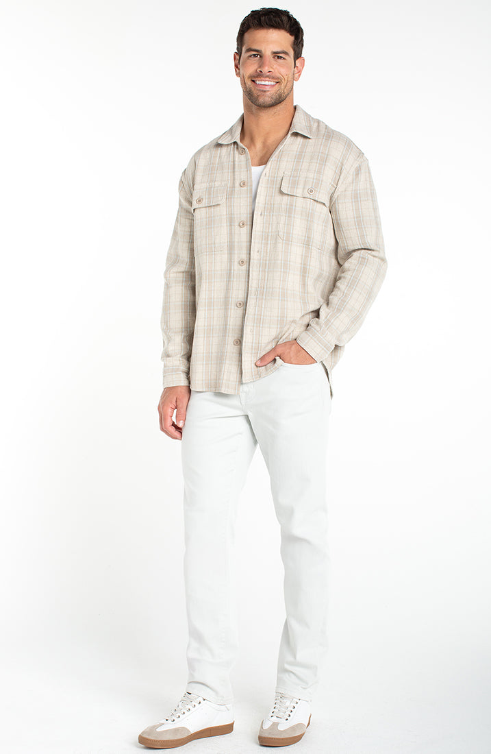 Full body view of men wearing oatmeal plaid overshirt with light pants and sneakers