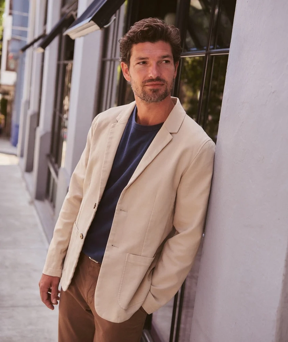 Man wearing Flex Terry Blazer in Dark Khaki leaning against wall, styled with navy tee and brown pants - The Simple Man