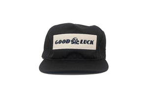Front view of the black Good Luck snapback hat with embroidered felt patch and skull logo, made in the USA.