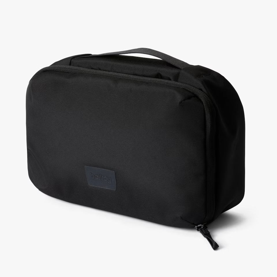 Bellroy black hanging toiletry kit shown closed on a counter, compact travel organizer for men from The Simple Man.