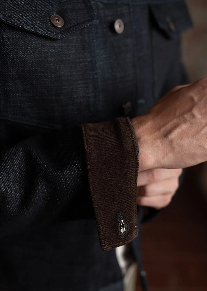 Close-up of cuff and button detail on men’s selvedge denim jacket