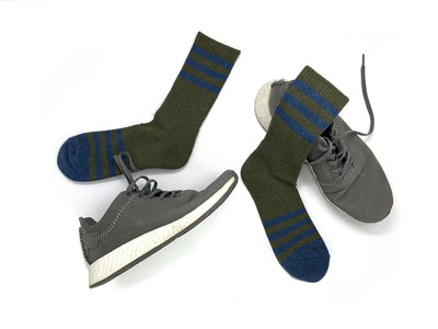 Men’s olive and navy striped socks worn with casual sneakers