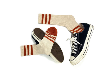 Men’s striped socks in heather oatmeal and orange worn with sneakers