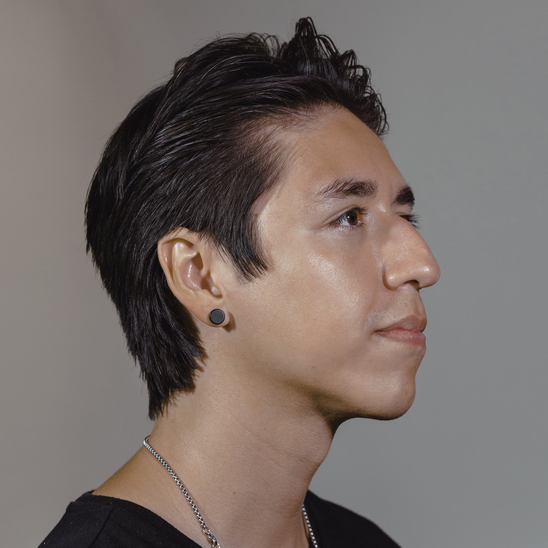 Young man with swept dark hair held in place by Heavymade, side profile