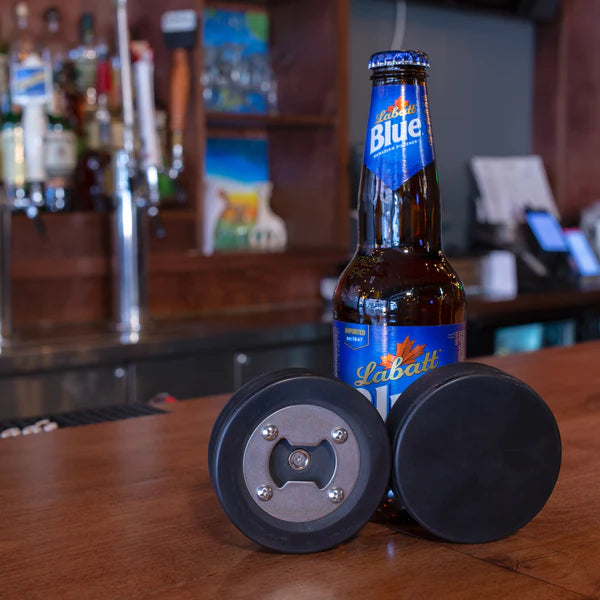 Hockey puck bottle opener, showing both top and bottom, with a beer bottle for reference