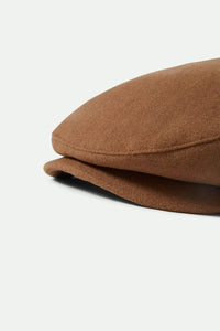 Side close-up of the Brixton Hooligan Flat Cap in camel highlighting the short brim and wool texture.