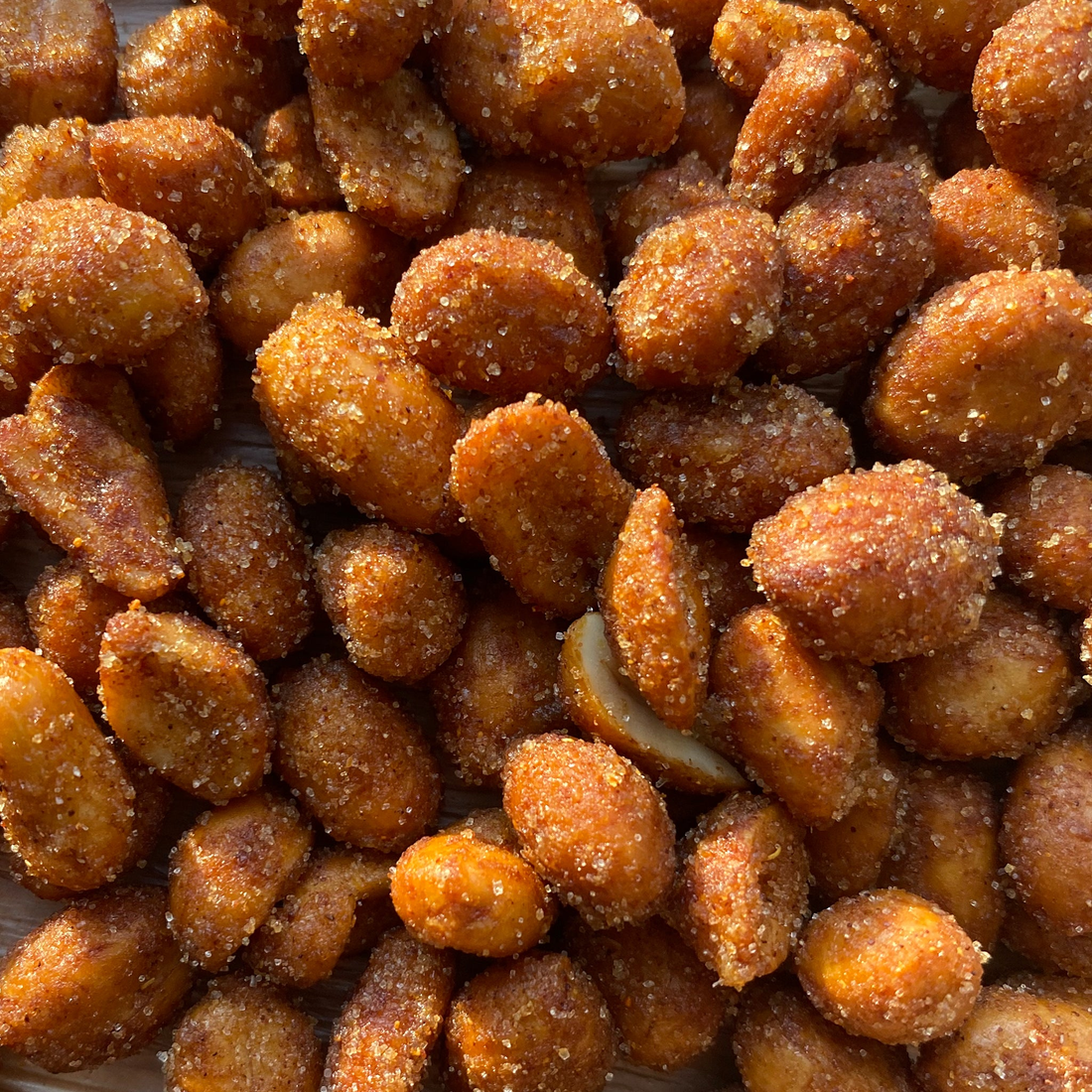 Honey roasted peanuts with a reddish hot BBQ seasoning coat, close detail view
