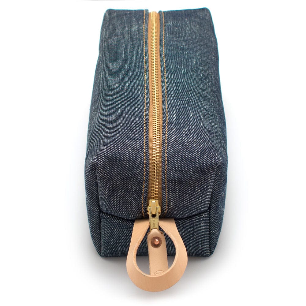 Detail of natural leather loop handle and zipper pull on rugged slubby Japanese denim toiletry bag from The Simple Man.