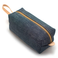 Angled top view of USA-made Japanese denim travel kit with full-grain leather accents and water-resistant canvas lining