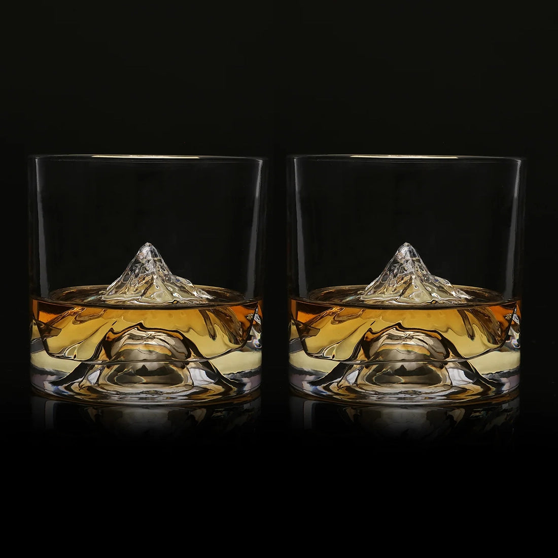 Set of two K2 Crystal Mountain Whiskey Glasses filled with bourbon, showcasing raised mountain design against a black backdrop.