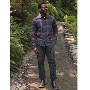 Man wearing Larson Shirt Cinder Plaid full length on wooded path, styled with dark pants and boots - The Simple Man