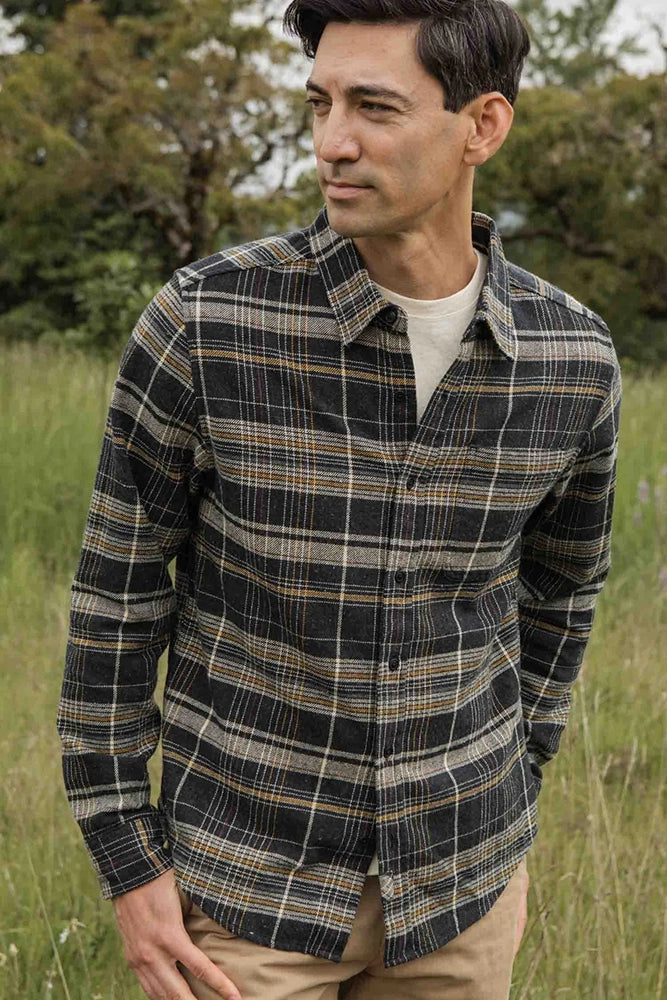 Man wearing The Larson plaid flannel shirt in volcanic colorway, styled casually outdoors with khaki pants.