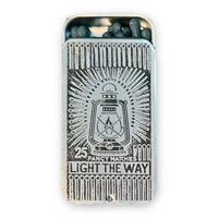 Metal matchbox with a lantern design and Light the Way on the lid, open to show dark-tipped matches