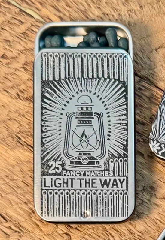 Matches in a tin with a lantern design on a wooden surface