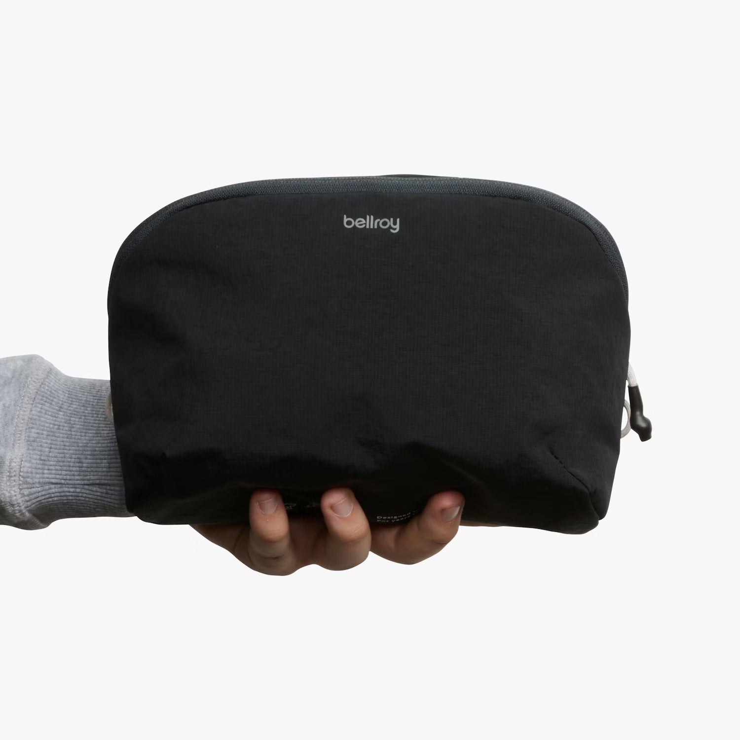 Black pouch with 'bellroy' branding held by a hand on a white background