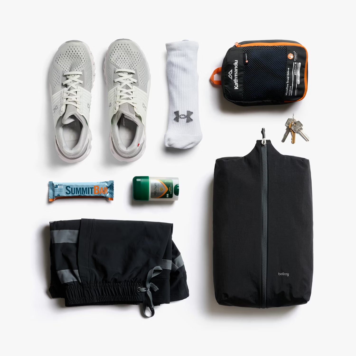 Collection of travel essentials including shoes, socks, a bag, and toiletries on a white background