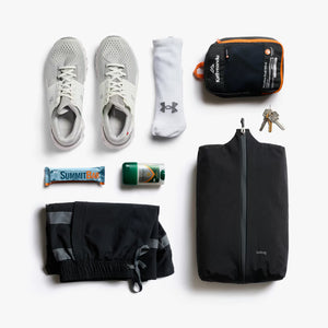 Collection of travel essentials including shoes, socks, a bag, and toiletries on a white background