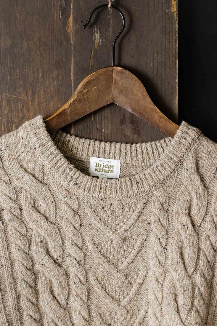 Close-up of The Ludlow Sweater by Bridge & Burn showing cable-knit merino wool texture in flecked oatmeal color, available at The Simple Man