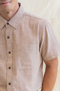Model wearing Bridge & Burn Malcom short sleeve chambray shirt in rust chambray color, front close up detail view
