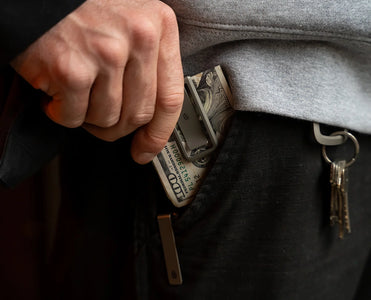 Man placing The Martindale titanium money clip with cash into front pocket – minimalist everyday carry