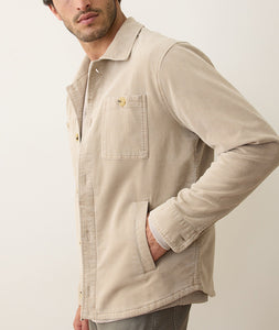 Man wearing taupe Max Moleskin Overshirt with double pockets and button front, viewed from the side with hand in pocket.