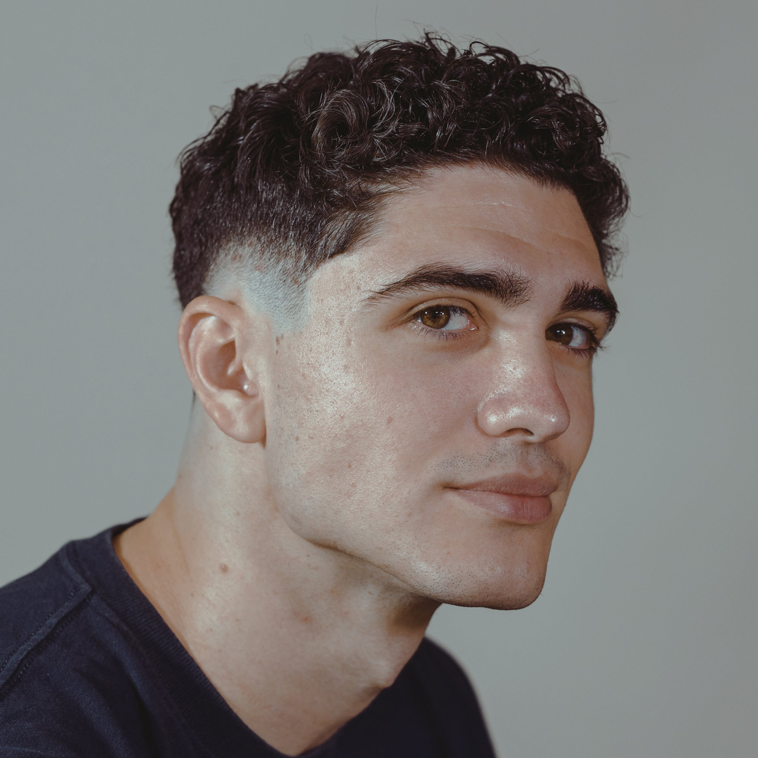 Short curly top with faded sides, styled with Modify Pomade