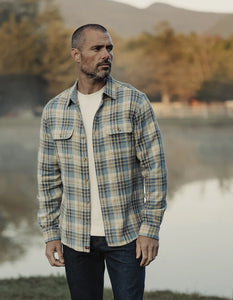 Men’s vintage blue plaid flannel overshirt styled casually with jeans, worn outdoors in a rugged Nebraska landscape—durable cotton shirt from The Simple Man.