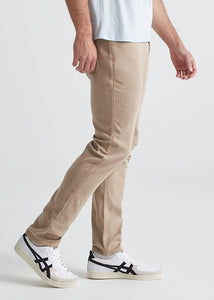 Model wearing Duer No Sweat Slim pants in Desert Khaki color, side view