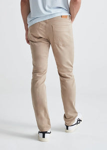 Model wearing Duer No Sweat Slim pants in Desert Khaki color, rear view