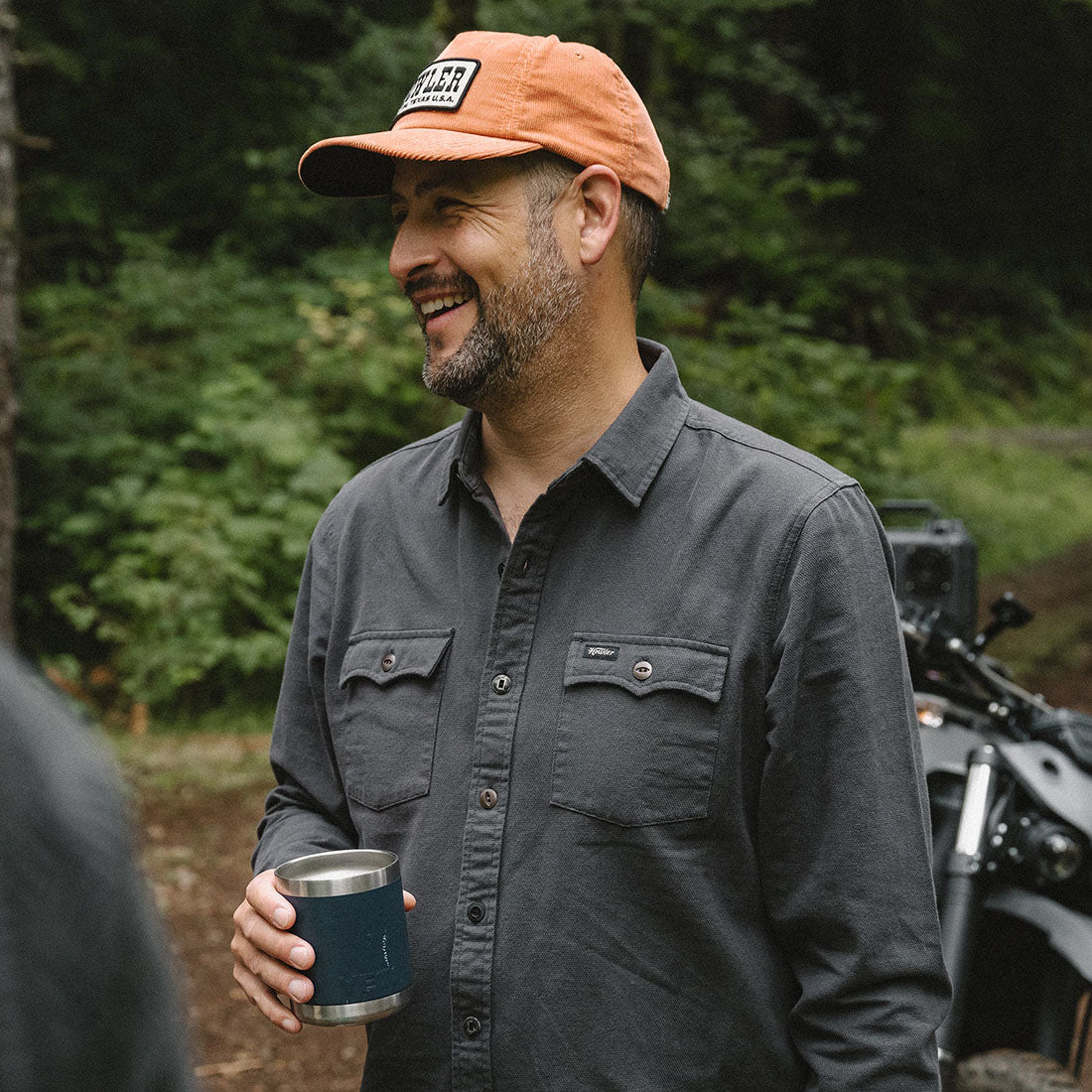 Man smiling outdoors wearing the Novato Shirt in Antique Black, charcoal grey cotton western snap shirt lifestyle shot -- The Simple Man