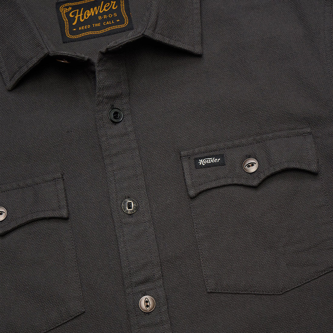 Close-up of chest pocket and collar on the Novato Shirt in Antique Black showing the Howler Bros label -- The Simple Man