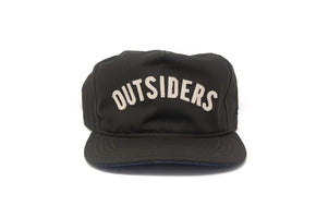 Front view of the OUTSIDERS Dry Wax Strapback with cream felt appliqué lettering on a black dry wax sailcloth cap