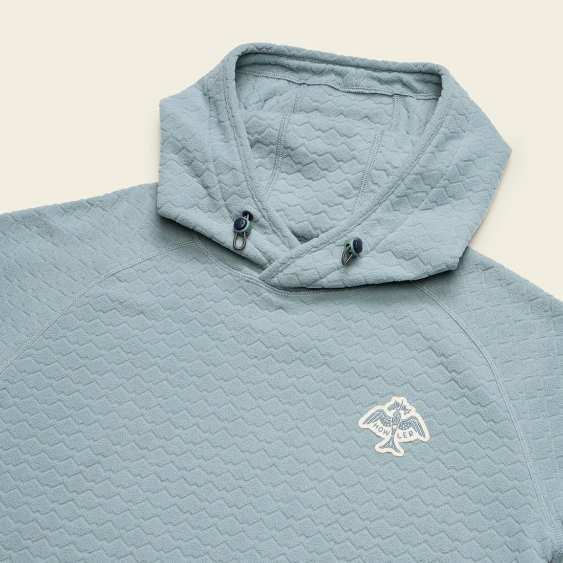 Detail of bungee drawcord hood and embroidered chest logo on blue fleece hoodie