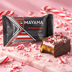 Peppermint mini chocolate bar in its wrapper beside a cut piece topped with crushed candy cane, on pink marble with candy canes, The Simple Man