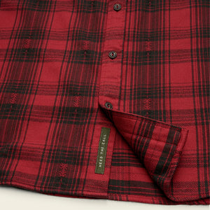 Close-up of Howler Brothers Quintana Flannel – Red and black plaid fabric with ‘Heed the Call’ tag at hem – The Simple Man