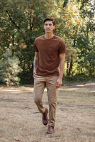 Man in Bridge and Burn bronze Recycled Pocket Tee walking outdoors with chinos and boots – sustainable men's everyday t-shirt