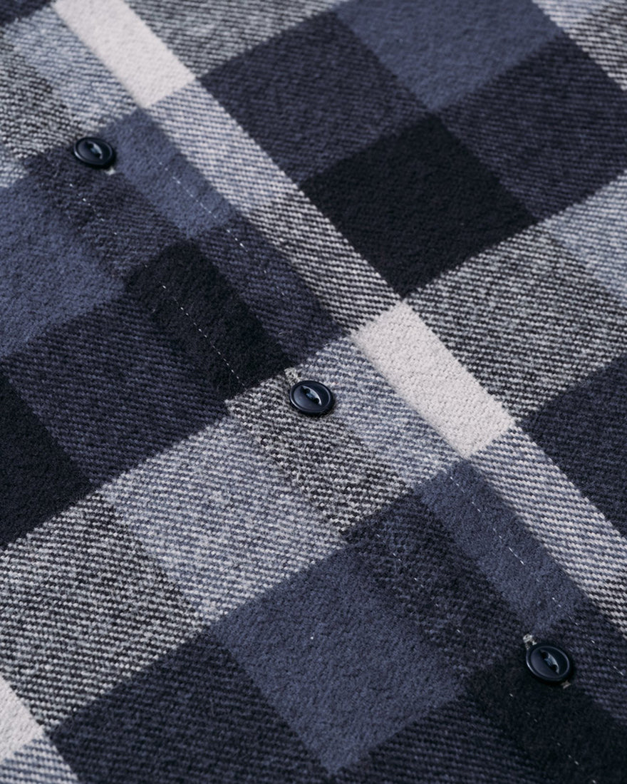 Close-up of blue and grey buffalo check flannel fabric with matte black buttons on 100% cotton men's shirt – rugged fall style from The Simple Man.