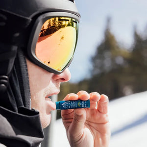 Oars+alps Spf lip balm 3pack in sunny mint flavor being applied on a skier's lips