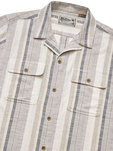 Detail of Howler Brothers Shores Club Shirt showing striped cotton fabric chest pockets and catseye buttons