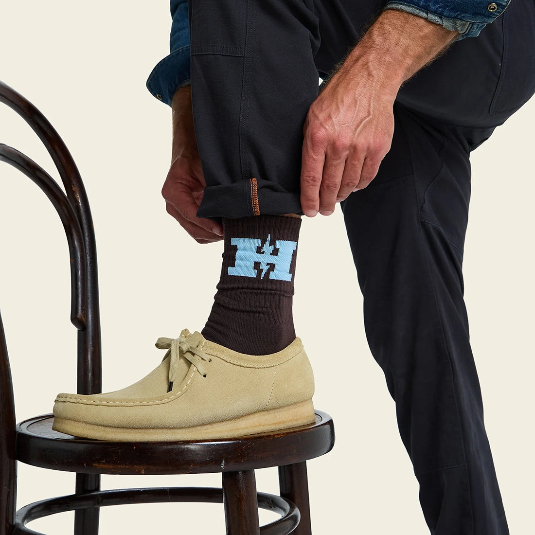 Man wearing H-Bolt Socks in Brown and Light Blue with suede moc-toe shoes, dark brown crew socks with light blue H Bolt graphic, lifestyle shot -- The Simple Man